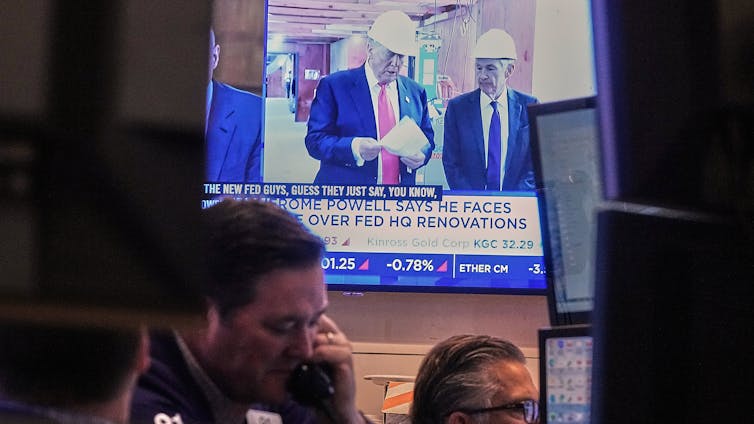 A screen shows men and a caption above other men working