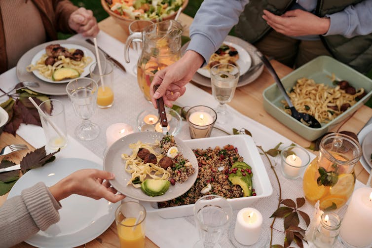 people enjoying a shared table meal, with only their arms visible