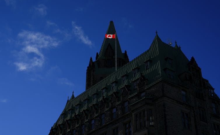 A Canada flag atop the Justice building on Parliament Hill catches the morning light.