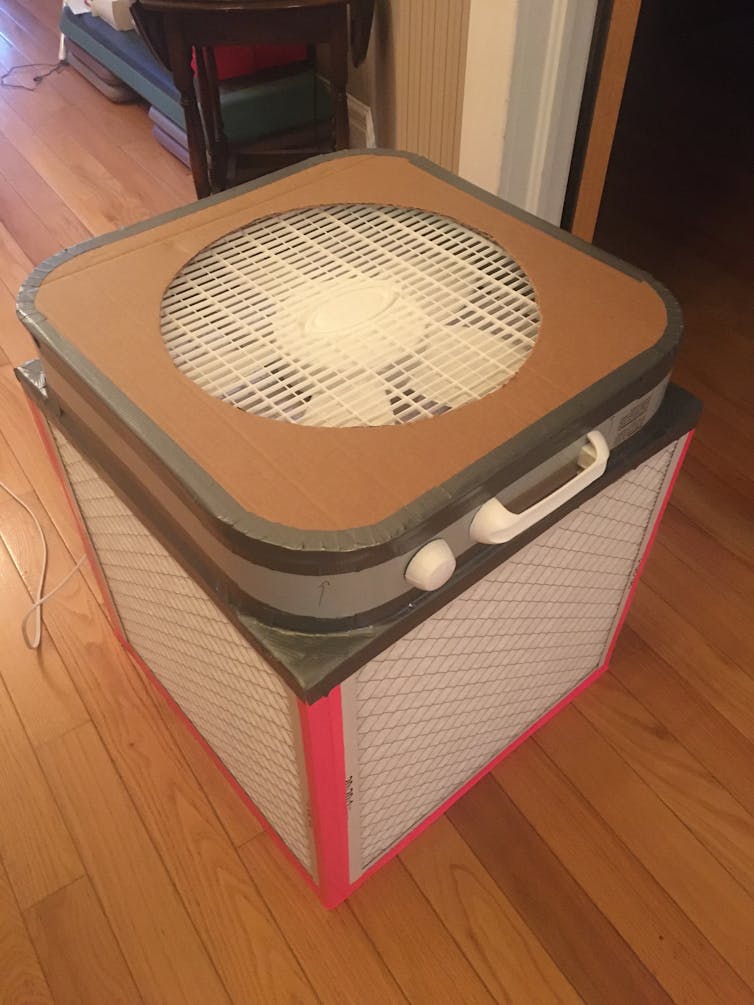 A box fan sits on top of a square of air filters.