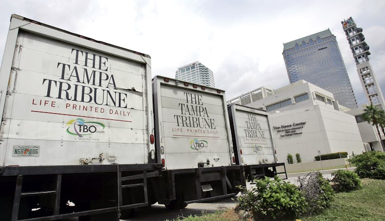 Backs of three trucks printed with 'The Tampa Tribune'