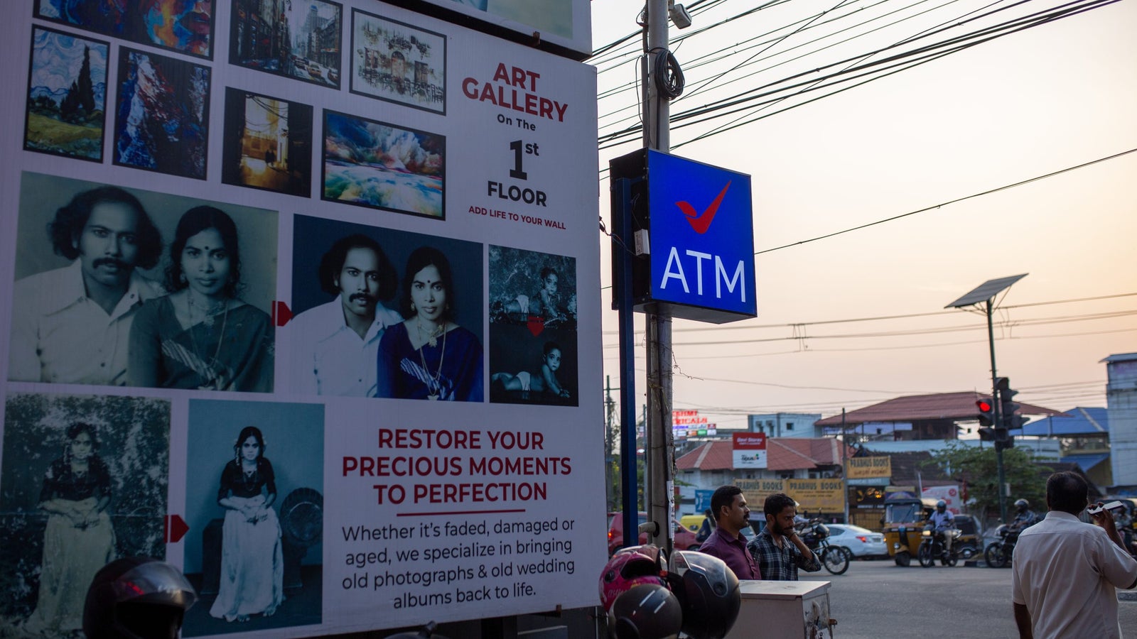 A large sign advertising an art gallery on the first floor, featuring a collage of photos and an ATM sign nearby.