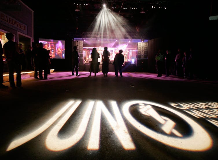 People dancing on a stage in front of a live band with the word 'junos' projected/