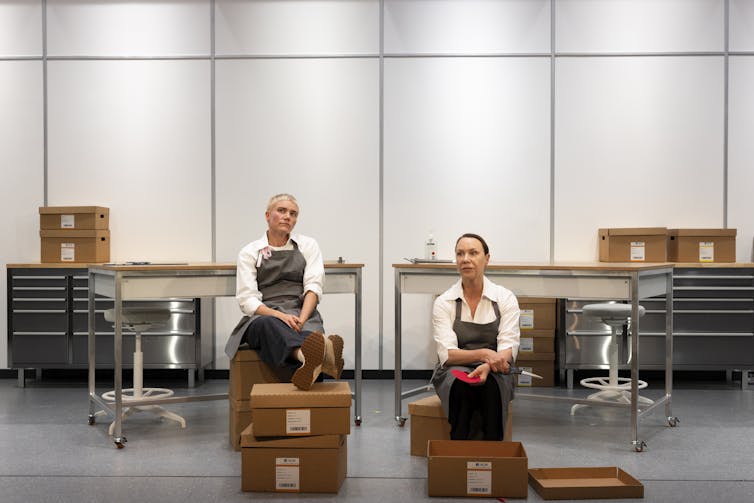 Production image: two people, a sterile room, lots of boxes.