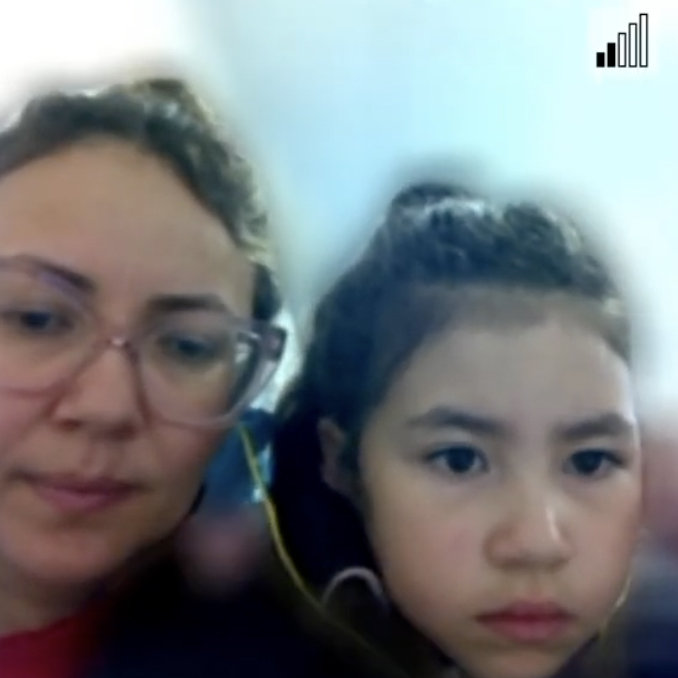 First of three screenshots of video calls. Bars indicating signal strength are in the top right of each image. In this one, a young girl sits next to a woman with glasses.