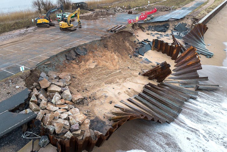 broken road and sea defence, digger in background