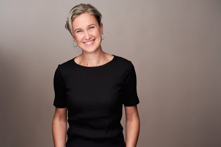a smiling woman in black with short blonde hair