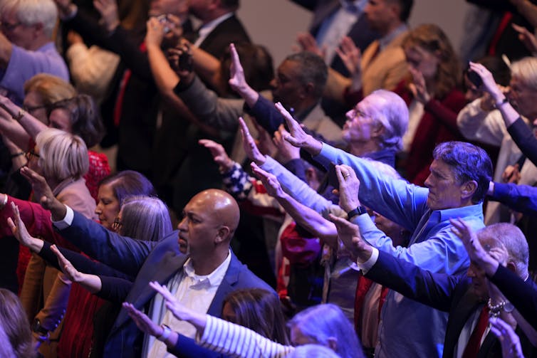 a group of people raise their arms in prayer