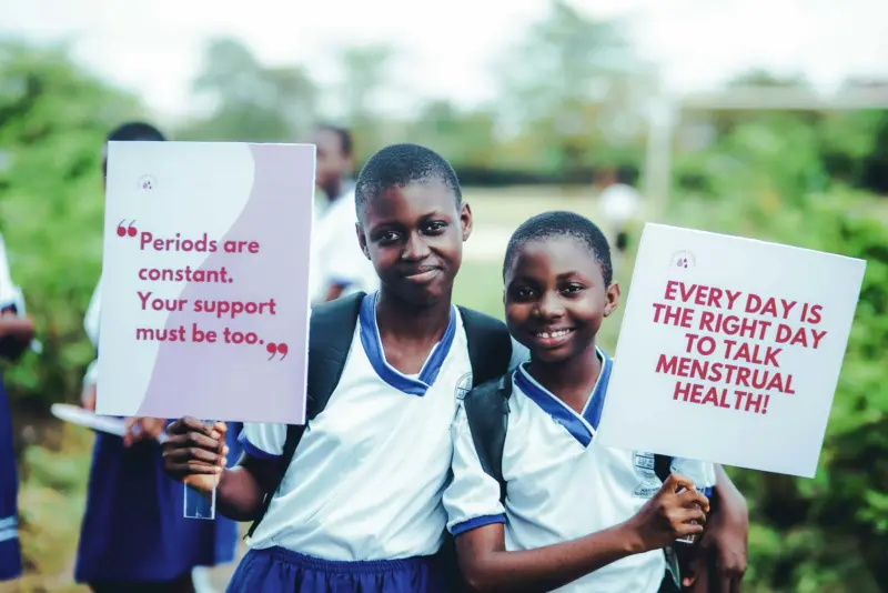 Nigerian schoolgirls holding signs calling for period justice.