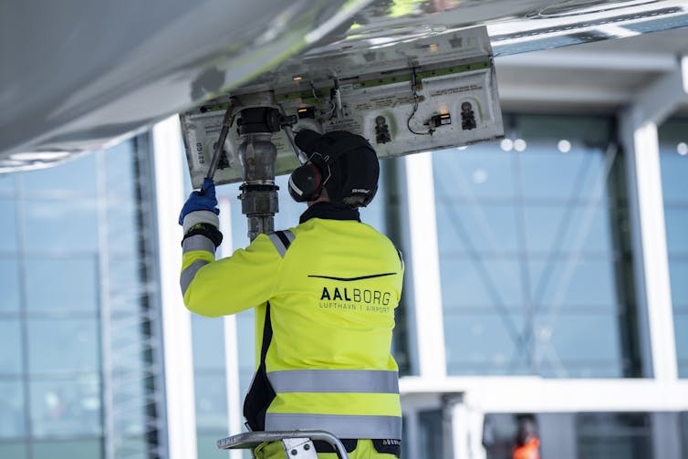 An airport worker fuels a plane