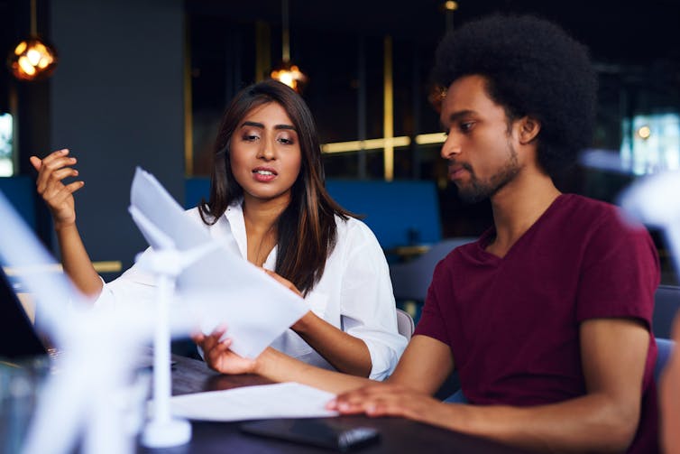 Two people sitting at a desk, having a conversation