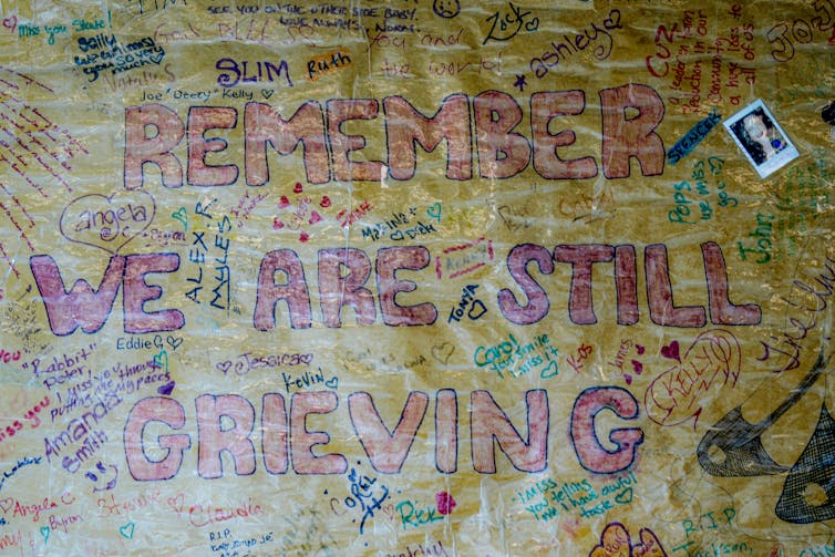 A wall mural reading Remember we are still grieving