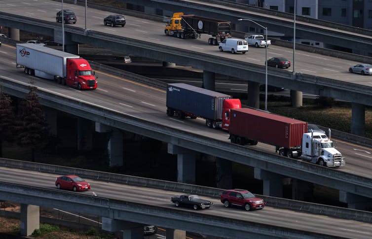An aerial view of a highway with several cargo trucks on it.