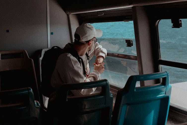 A young man looking out a bus window.