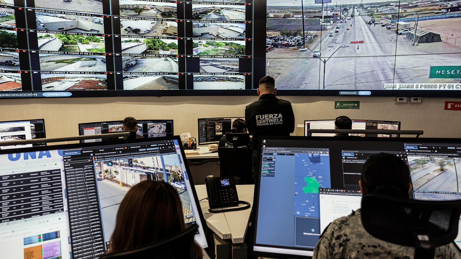 A control room with multiple large screens displaying surveillance footage, and operators monitoring activities at their desks.