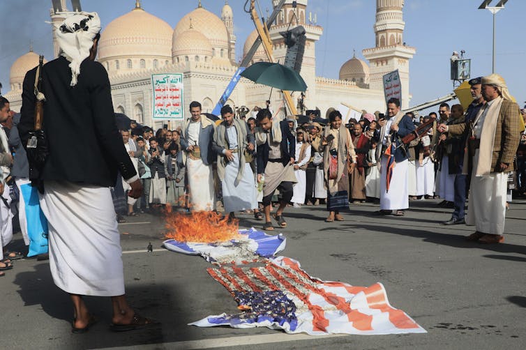 Protesters burn flags at a demonstration.