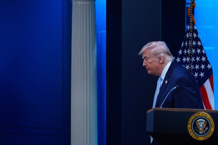 A man in a suit walks away from a lectern.