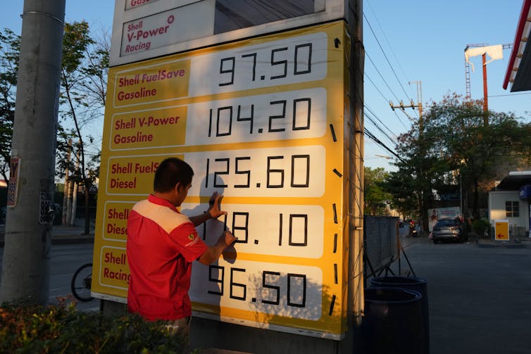 A man adjuusts fuel prices on a sign