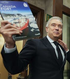 a man in a suit holds a document that says Canada strong.