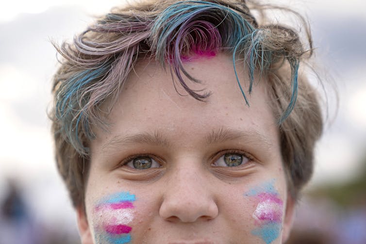 A closeup of a person's face with face paint and hair colouring.