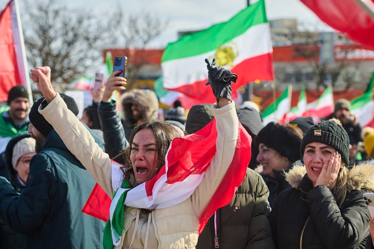 A group of demonstrators raising flags with distressed looks on their faces.