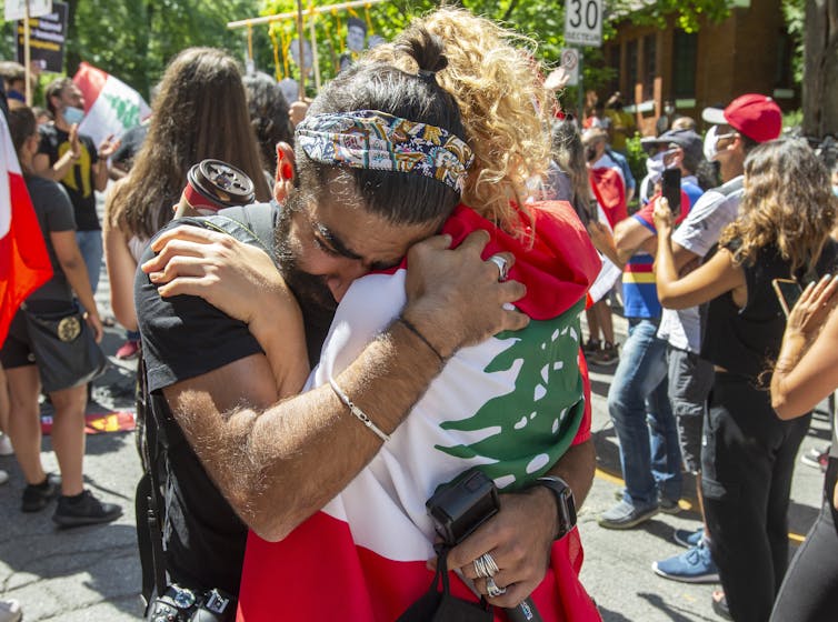 A group of protesters walk behind a closeup of two people hugging