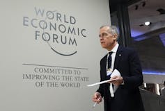 A man in suit walks on a stage.