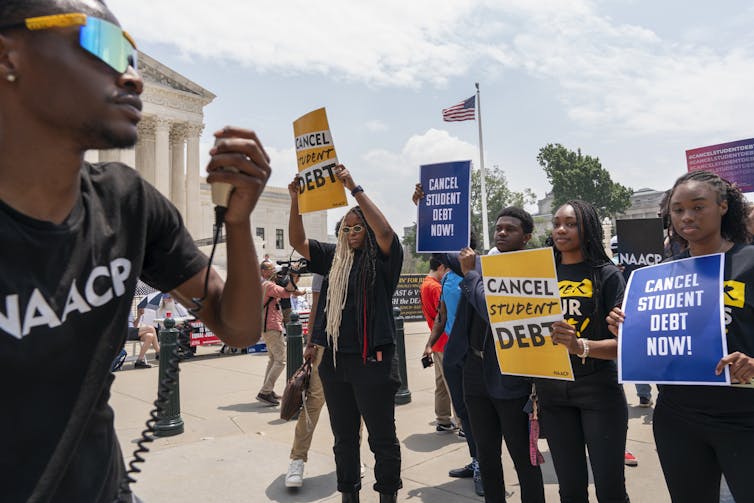 Students seen with signs that say 'cancel student debt.'
