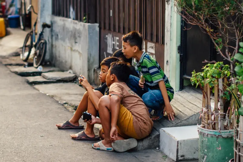 Three tween boys crowd around a mobile phone in Jakarta, Indonesia.