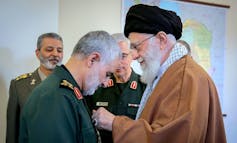 A man pins a medal on another man's lapel