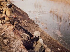 two soldiers wearing gas masks and holding rifles