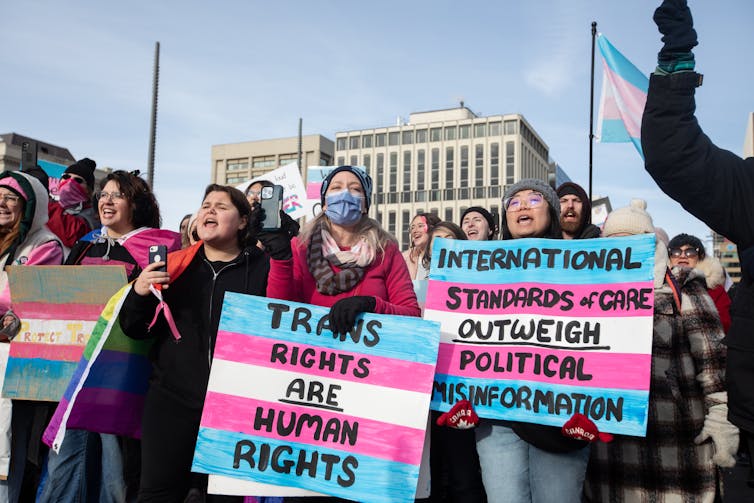 A group of people holding signs protesting against anti-trans policies
