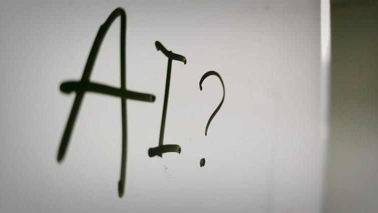 A white board with the word AI written on it followed by a question mark.