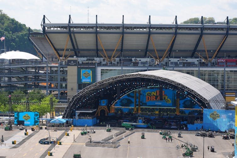 A wide shot of a parking lot and stage with a stadium behind it.