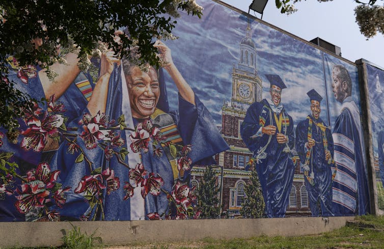 Mural showing many Black graduates in robes and caps at a celebration.