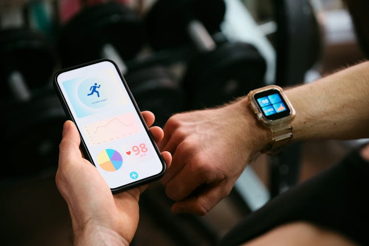 A close-up of a man holding a phone in his left hand and a smart watch on his right wrist.