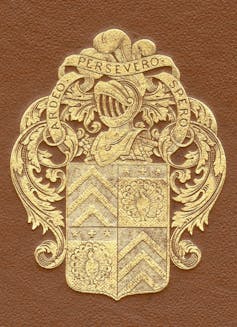 A brown manuscript cover featuring a gold coat of arms with a knight's helmet and shield.