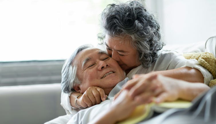 an older asian couple cuddle