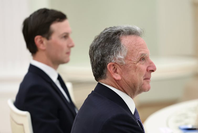 An older man and a younger dark-haired man photographed in profile.