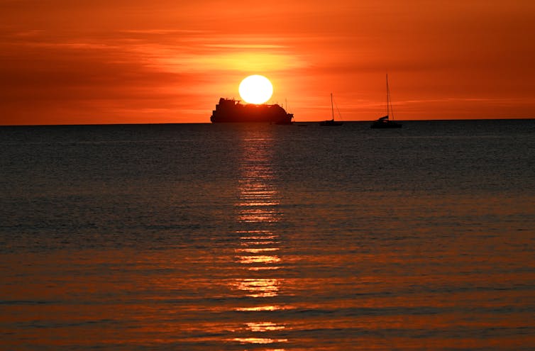 A ship in front of a red and orange sunset.