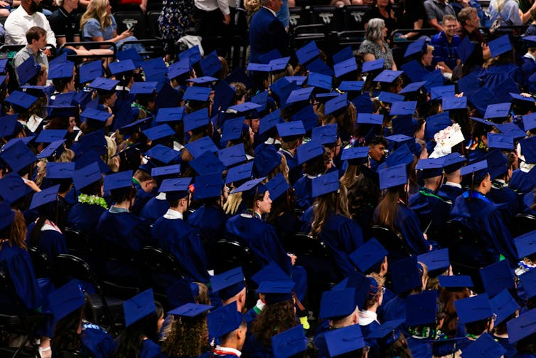 A sea of graduate caps as grads are seated in rows at a ceremony.