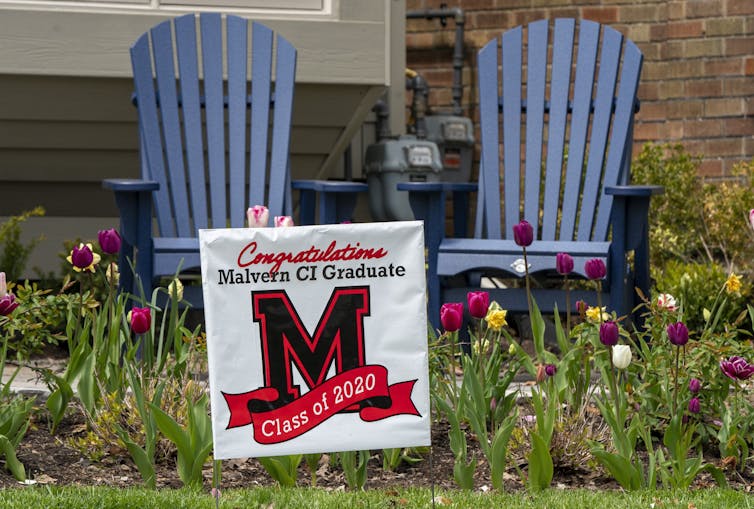 A lawn sign in front of wooden lawn chairs says congratulations class of 2020.