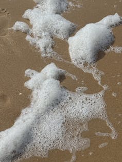 White sea foam on a sandy beach.