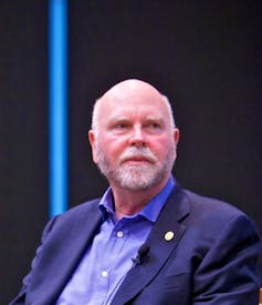 J. Craig Venter in a suit at a conference, looking off-camera