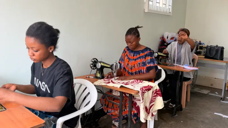Three young girls sewing with a sewing machine