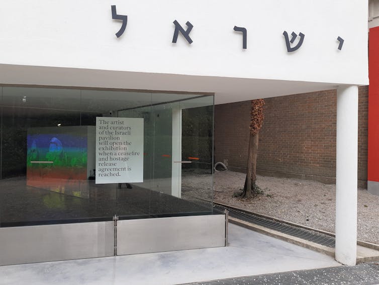Sign reads: 'The artist and curators of the Israeli pavilion will open the exhibition when a ceasefire and hostage release agreement is reached'