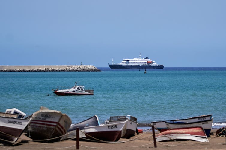 A boat is seen from a shore littered with various watercraft