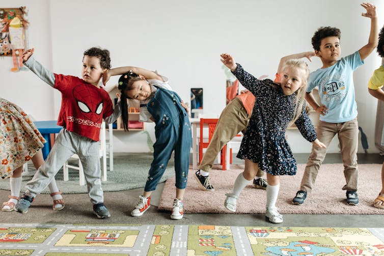 Children standing in a row doing movements.