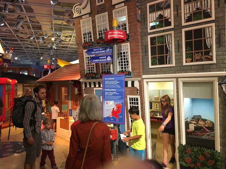 Adults and kids seen milling about a museum display.