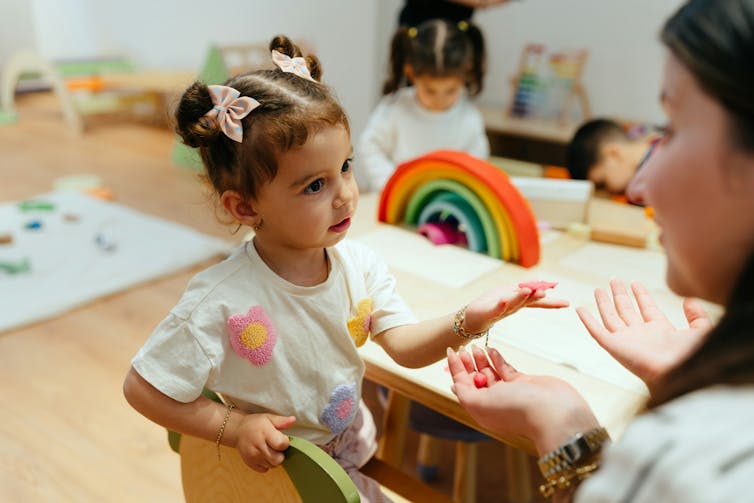 A child and adult in discussion at a table.